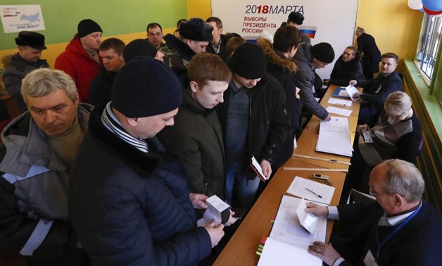 People queue before receiving their ballots and casting their votes at a polling station during the presidential election in Moscow, Russia March 18, 2018.