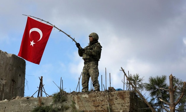 A Turkish soldier waves a flag on Mount Barsaya, northeast of Afrin - REUTERS
