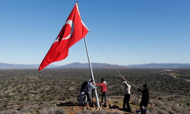 Villagers fix a broken flagpole in Sugedigi village on the Turkish-Syrian border in Hatay province, Turkey, January 2018. REUTERS