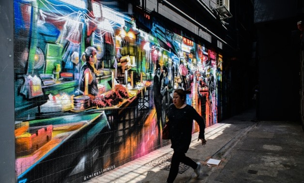 A pedestrian runs past a mural spray painted by British artist Dan Kitchener in an alleyway near a market in the Wanchai district of Hong Kong