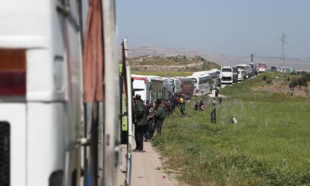 A convoy transporting Syrian civilians and rebel fighters evacuated from Eastern Ghouta waits in a government-held area prior to entering the village of Qalaat al-Madiq, some 45 kilometres northwest of the central city of Hama, on March 26, 2018
