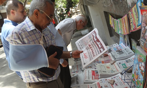 FILE - An Egyptian citizen checks out a morning newspaper at a roadside newspapers stand. 