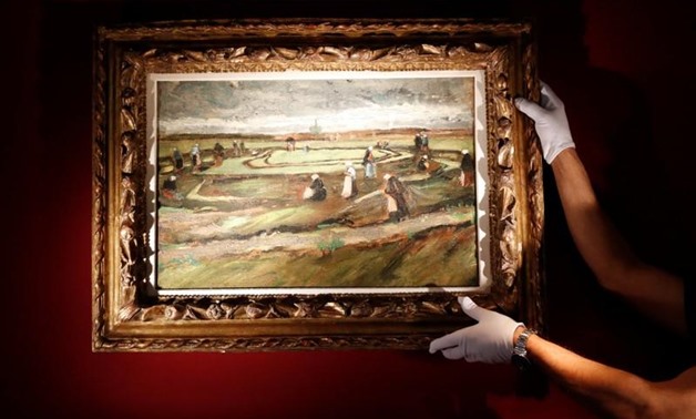 Artcurial's employee poses as he holds the painting "Raccommodeuses de filets dans les dunes, 1882" (Women Mending Nets in the Dunes) by painter Vincent Van Gogh (1853-1890) during a preview for media at Artcurial Auction House in Paris, France March 28, 