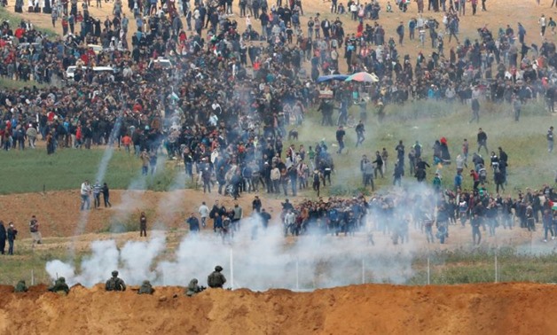 Israeli soldiers fire tear gas as thousands of Gazans march just across the border fence sparking clashes in which four Palestinians were killed and more than 200 wounded (AFP Photo/Jack GUEZ )
