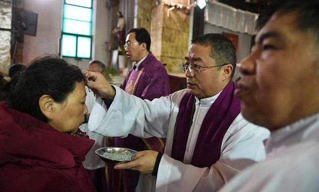 A priest marks the forehead of a worshipper with ash during the Ash Wednesday mass - AFP

