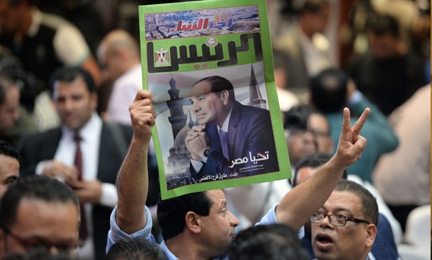  An Egyptian man carries a copy of a newspaper, bearing the portrait of Egyptian President Abdel Fattah al-Sisi, during a press conference by the National Elections Authority in Cairo on April 2, 2018, to announce official result of Egypt presidential ele