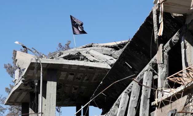 A flag of Islamic State militants is pictured above a destroyed house near the Clock Square in Raqqa, Syria October 18, 2017. REUTERS/Erik D