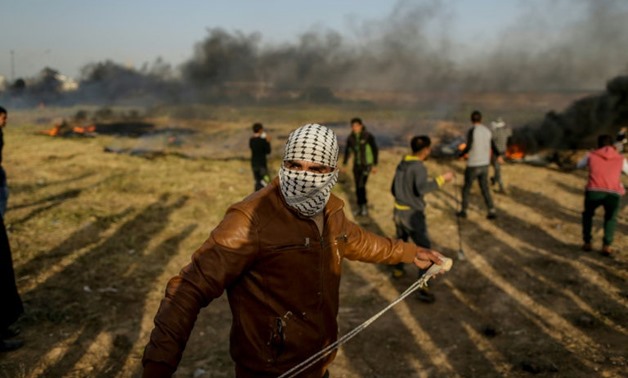 A Palestinian protestor uses a slingshot to throw a stone during clashes with Israeli forces at the Israel-Gaza border east of Gaza City on April 4, 2018
