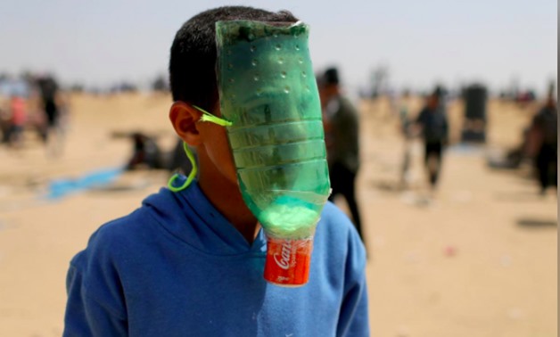 A Palestinian protects himself from inhaling tear gas at the Israel-Gaza border during a protest demanding the right to return to their homeland, in the southern Gaza Strip April 6, 2018. REUTERS/Ibraheem Abu Mustafa
