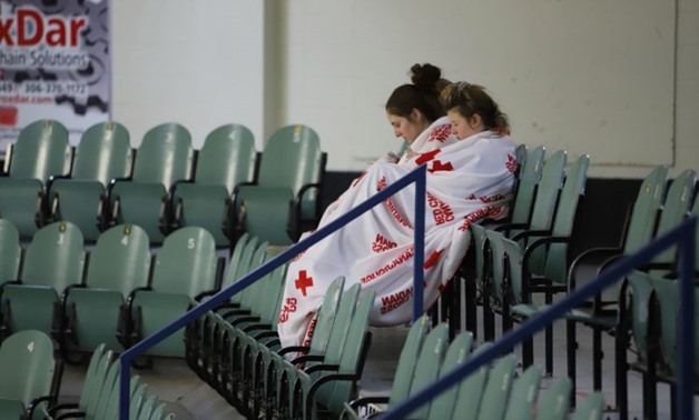Two girls sit amid empty seats at an ice-skating rink in the small Canadian town of Humboldt, which is preparing an evening vigil to honor the local hockey players and coaches killed in a crash
