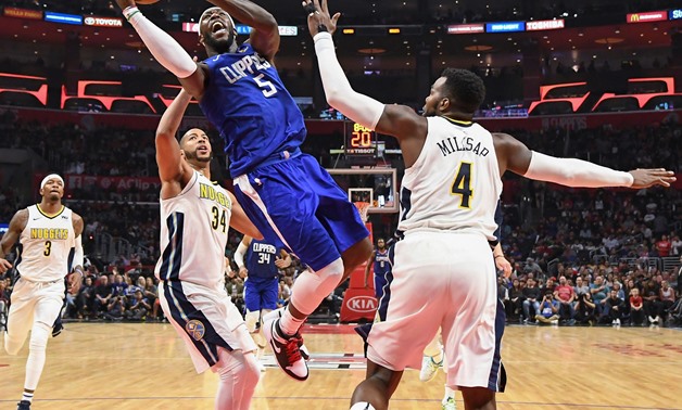 Apr 7, 2018; Los Angeles, CA, USA; LA Clippers forward Montrezl Harrell (5) drives to the basket between Denver Nuggets guard Devin Harris (34) and Denver Nuggets forward Paul Millsap (4) during the second half at Staples Center. Mandatory Credit: Robert 