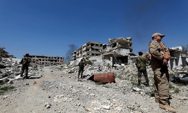 Members of Syrian forces of President Bashar al Assad stand guard near destroyed buildings in Jobar, eastern Ghouta, in Damascus, Syria April 2, 2018. REUTERS/Omar Sanadiki/File Photo