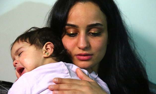 Twenty-three year old Islam Maytat from Morocco comforts one of her two children, Maria - AFP 