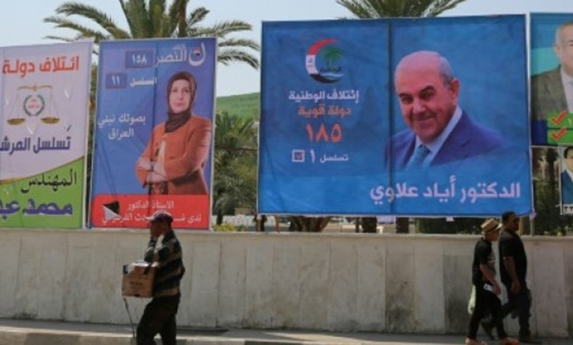 © AFP | People walk past campaign posters in the Iraqi capital Baghdad ahead of the upcoming May parliamentary election
