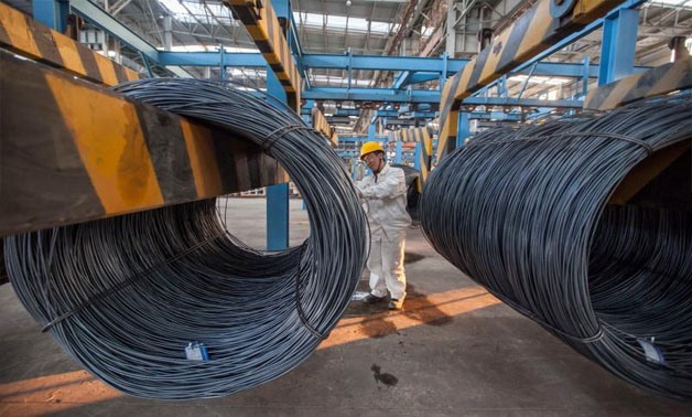 An employee inspects newly-made steel coils at a steel plant in Lianyungang, Jiangsu province October 11, 2014 - REUTERS/China Daily