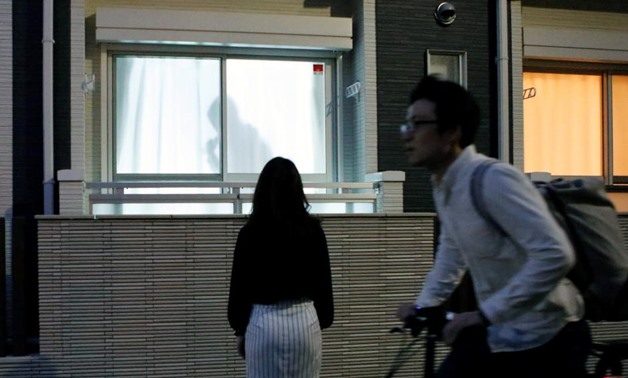 Leopalace 21 Corp employee, Mai Shibata, poses in front of a window, on which the company's security system 'Man on the Curtain' projects a man's shadow, in Tokyo, Japan, April 20, 2018. REUTERS/Kwiyeon Ha
