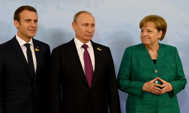 German Chancellor Angela Merkel poses with French President Emmanuel Macron (L) and Russia’s President Vladimir Putin (C). The three leaders agreed to exert “maximum pressure” on Syria for an “immediate” implementation of a UN cease-fire. (File Photo: AFP