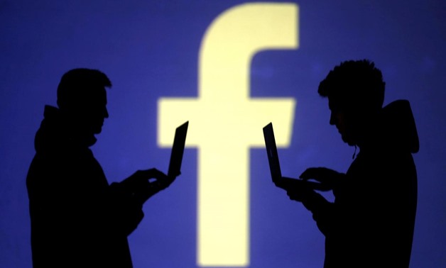 FILE PHOTO: Silhouettes of laptop users are seen next to a screen projection of Facebook logo in this picture illustration taken March 28, 2018.
