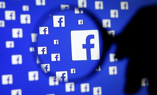 A man poses with a magnifier in front of a Facebook logo on display in this illustration taken in Sarajevo, Bosnia and Herzegovina, December
