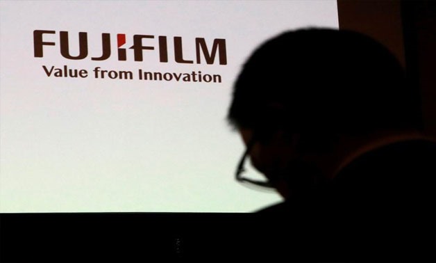 A man is silhouetted in front of Fujifilm Holdings' logo ahead of its news conference in Tokyo, Japan January 31, 2018 - REUTERS/Kim Kyung-Hoon