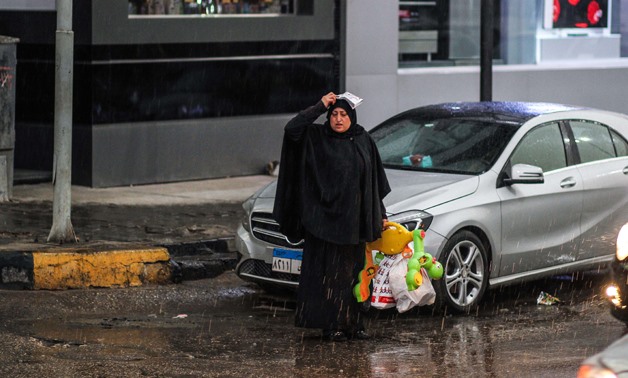 A woman covers herself from the rain in al-Batal Ahmed Abdel-Aziz street, Mohandeseen, Giza - EgyptToday