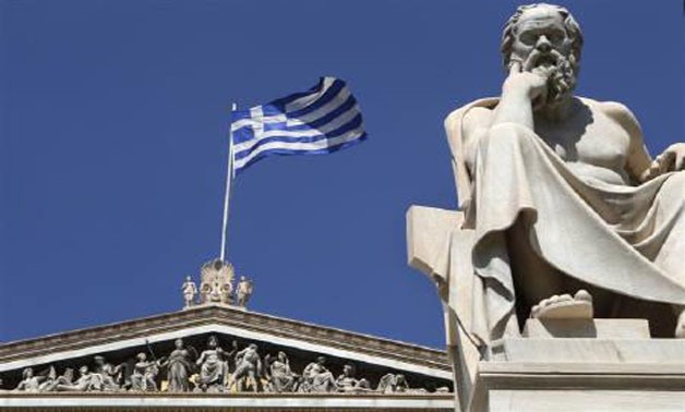 A Greek flag flutters behind a statue of ancient philosopher Socrates at the the Academy of Athens, July 23, 2010 - REUTERS/John Kolesidis/Files