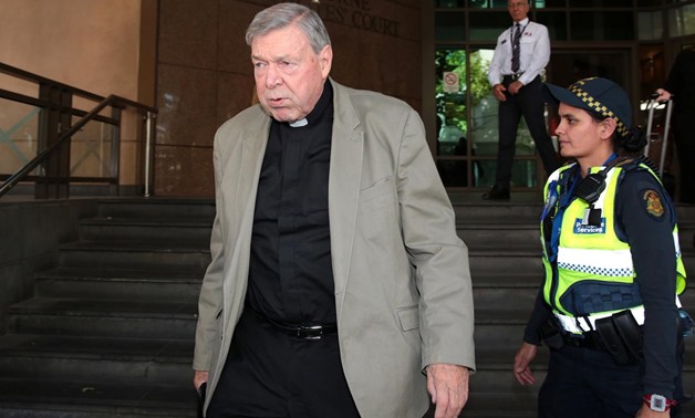 Vatican treasurer Cardinal George Pell is watched by a security guard and an Australian police officer as he leaves Melbourne Magistrates' Court in Australia, March 19, 2018. AAP/Stefan Postles/via REUTERS