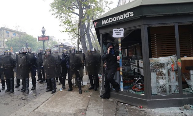 CRS riot police officials stand next to a damaged McDonald's resteraunt during a demonstration on the sidelines of a march for the annual May Day workers' rally in Paris
