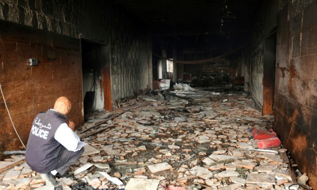 A Libyan policeman inspects damage at the Libyan electoral commission headquarters in Tripoli after it was targeted by suicide bombers on May 2, 2018
