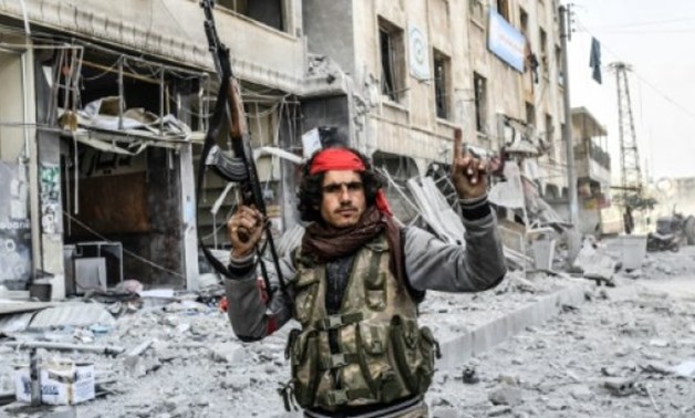 © AFP | A Turkish-backed Syrian rebel poses in front of a destroyed building in the northern city of Afrin which Ankara-led forces captured from Kurdish fighters
