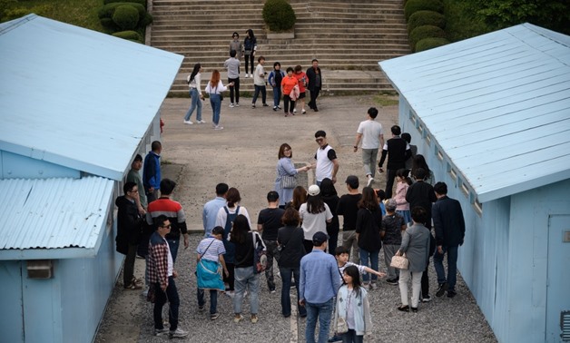 Visitors stand before a mock military demarcation line as they pose for photos at a replica of the DMZ border truce village of Panmunjom, built as a film set, near Namyangju, east of Seoul on May 5, 2018. (AFP/Ed Jones)