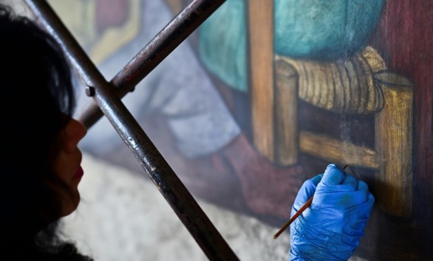 An expert restores a mural by Diego Rivera, whose painting 'The Rivals' now holds the record for the highest price paid at auction for a Latin American artwork-AFP/File / RONALDO SCHEMIDT

