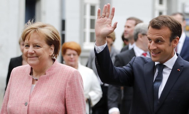French President Emmanuel Macron waves next to German Chancellor Angela Merkel as he arrives to receive a Charlemagne Prize in Aachen, Germany May 10, 2018.
