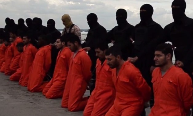 Men in orange jumpsuits, identified to be Egyptian Christians, held captive by the Islamic State (IS) are marched by armed men along a beach said to be near Tripoli, in this still image from an undated video made available on social media on February 15, 