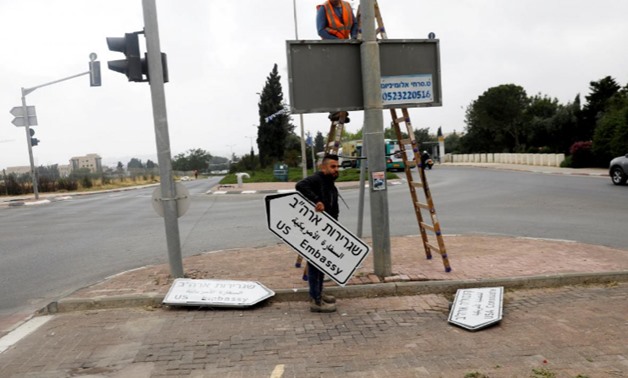 A worker holds a road sign directing to the US embassy in Jerusalem on May 7, 2018 – Reuters/Ronen Zvulun