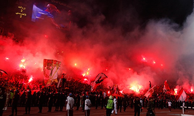 Fans wave flags and light flares as police in riot gear stand guard during the Egyptian Premier League soccer match between Ahly and Zamalek in Cairo June 29, 2011, Reuters 