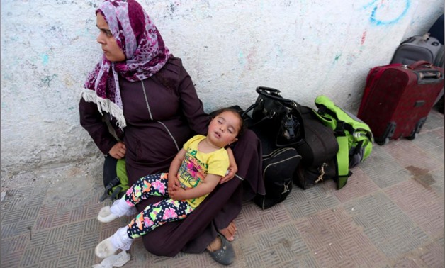 A Palestinian girl sleeps as she waits with her mother to travel to Egypt through the Rafah border crossing, in the southern Gaza Strip May 18, 2018. REUTERS/Ibraheem Abu Mustafa
