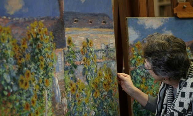 Ann Hoenigswald, senior conservator of paintings at the National Gallery of Art, looks at "The Artist's Garden at Vetheuil" (1881) by Claude Monet, unframed, with a version held by the Norton Simon Museum in the background.