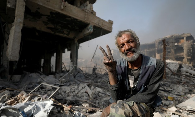 A man gestures as he sits on the rubble of damaged buildings in al-Hajar al-Aswad, Syria May 21, 2018. REUTERS/Omar Sanadiki
