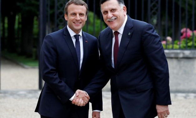 French President Emmanuel Macron stands between Libyan Prime Minister Fayez al-Sarraj (L), and General Khalifa Haftar (R), commander in the Libyan National Army (LNA), who shake hands after talks over a political deal to help end Libya’s crisis in La Cell