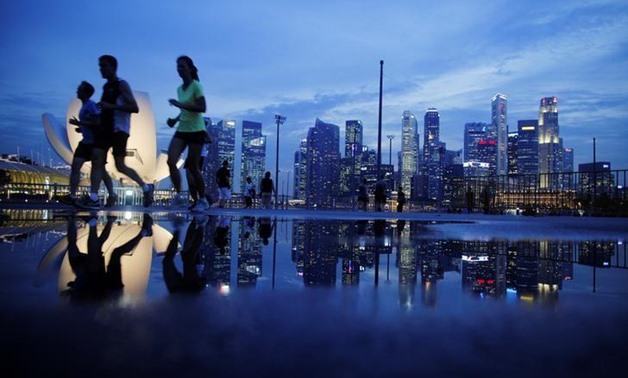 Joggers run past as the skyline of Singapore's financial district is seen in the background April 21, 2014. REUTERS/Edgar Su/File Photo