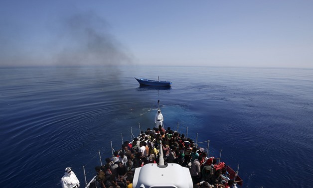 RESCUED: Italian police carry migrants to safety, leaving their leaky boat to drift – REUTERS/Alessandro Bianchi