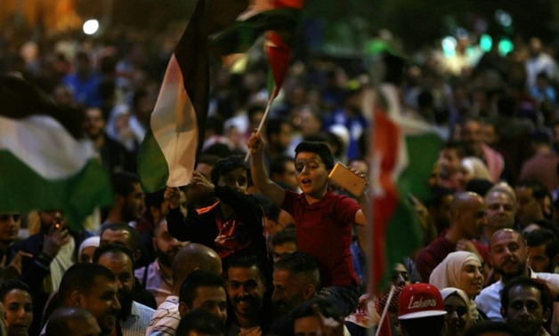 Children wave flags during a protest near the prime minister's office in Amman, Jordan, on June 4, 2018
