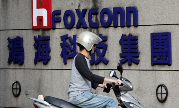 FILE PHOTO: A motorcyclist rides past the logo of Foxconn, the trading name of Hon Hai Precision Industry, in Taipei, Taiwan March 30, 2018. REUTERS/Tyrone Siu/File Photo