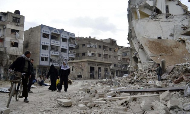 Residents walk past damaged buildings after what activists said were air strikes by forces loyal to Syria's President Bashar al-Assad in the Douma neighborhood of Damascus February 6, 2015. REUTERS/Amer Almohibany
