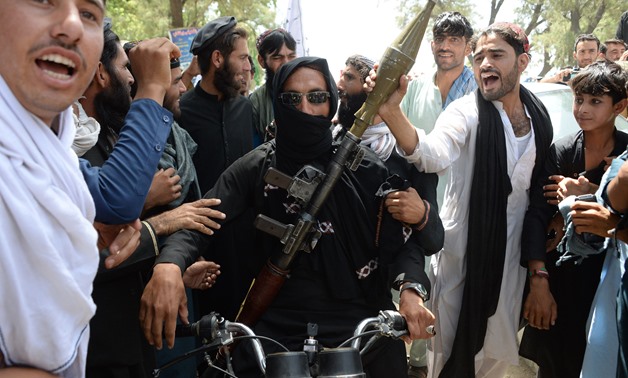 An Afghan Taliban militants carries a rocket-propelled as he looks on with residents as they took to the street to celebrate ceasefire on the second day of Eid in the outskirts of Jalalabad on June 16, 2018- AFP
