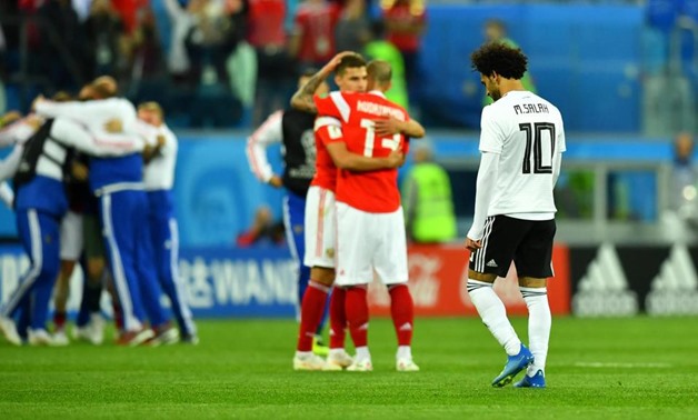 Egypt's Mohamed Salah makes his way off the pitch as two Russia players celebrate at full time. Dylan Martinez / Reuters