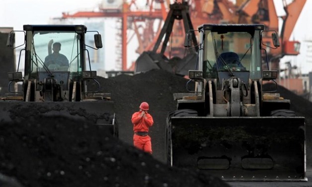 FILE PHOTO - An employee walks between front-end loaders which are used to move coal imported from North Korea at Dandong port in the Chinese border city of Dandong, Liaoning province December 7, 2010. REUTERS/Stringer/File Photo
