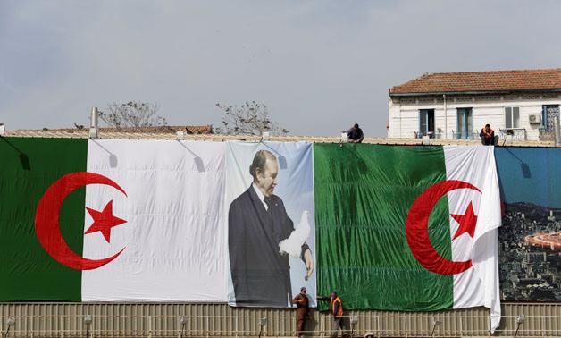 Algerian city employees install Algerian flags and President's Abdelaziz Bouteflika poster on the streets ahead of the Parliamentary election in Algiers, Algeria April 26,2017. REUTERS/Ramzi Boudina