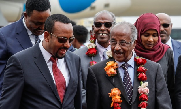 Ethiopia's Prime Minister Abiy Ahmed talks with Eritrea's top diplomat Osman Saleh, wearing a garland, as the two met for a landmark meeting aimed at ending decades of conflict between their two countries
